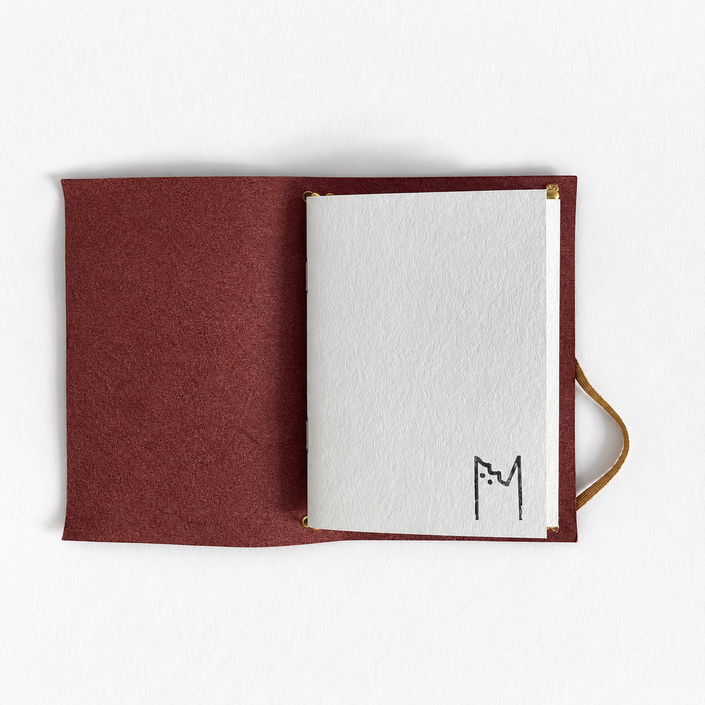 Carnet Armérie en cuir prune, ouvert sur ses carnets de papier recyclé